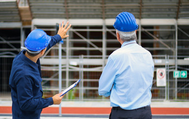 Two architect developers reviewing building plans at construction site