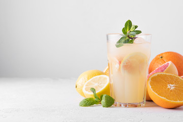 Summer refreshing lemonade with mint on a light background. A glass of citrus cocktail in a light key. Close up. Summer Vitamin cocktail of orange, lemon and grapefruit.