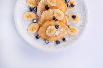 pancakes with banana and blueberries on a white plate, tasty and beautiful on a white background
