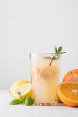 Summer refreshing lemonade with mint on a light background. A glass of citrus cocktail in a light key. Close up. Summer Vitamin cocktail of orange, lemon and grapefruit.
