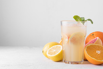 Summer refreshing lemonade with mint on a light background. A glass of citrus cocktail in a light key. Close up. Summer Vitamin cocktail of orange, lemon and grapefruit.