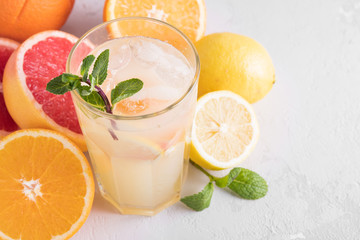 Summer refreshing lemonade with mint on a light background. A glass of citrus cocktail in a light key. Close up. Summer Vitamin cocktail of orange, lemon and grapefruit.