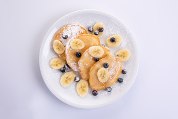 pancakes with banana and blueberries on a white plate, tasty and beautiful on a white background