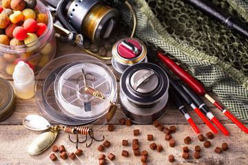 Fishing rods and spinnings in the composition with accessories for fishing on the old background on the table