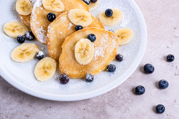 pancakes with banana and blueberries on a white plate, tasty and beautiful