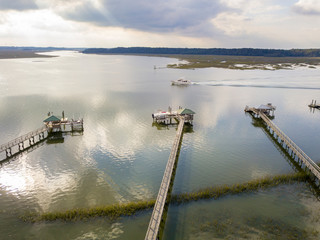 Aerial shot of yacht passing by docks and boathouse on a river in South Carolina.