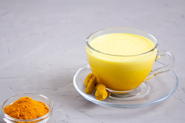 Golden milk in a glass gray cup on a gray background