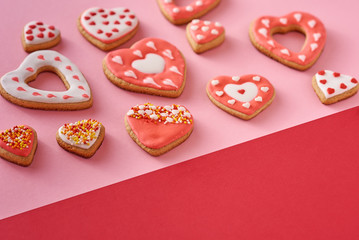 Decorated heart shape cookies on a colored red and pink background, top view