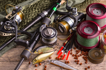 Fishing rods and spinnings in the composition with accessories for fishing on the old background on the table © vizafoto