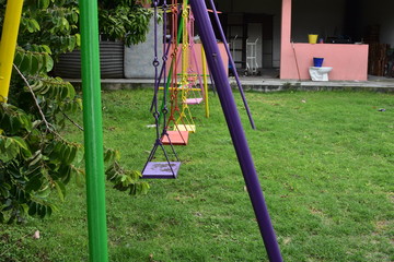 Fototapeta premium columpios multicolores de fierro con fondo de pared rosa