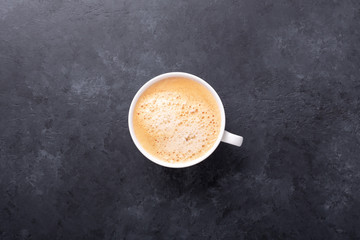 Cup of coffee on black stone background. Top view. Copy space.