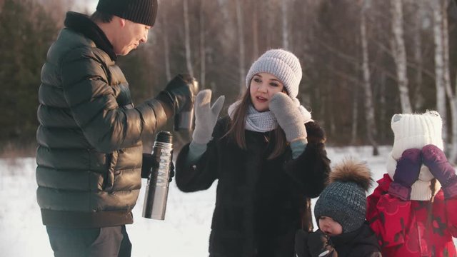 Family drinking hot drinks from the termos in winter time
