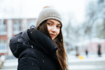 girl in a cap and a warm jacket on a background of a snowy street