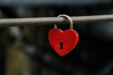 Red heart lock on a bridge as a symbol for love like valentines day or wedding, space for text, nobody and horizontal