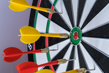 Red and yellow dart arrows hitting in the target center of dartboard. Success hitting target aim goal achievement concept