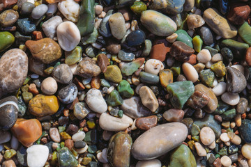 Closeup top view of many colorful vivid smooth stones at sea beach. Abstract organic background. Horizontal flatlay color photography.