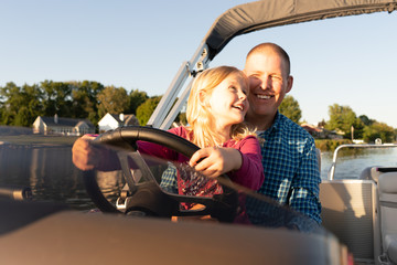 You girl driving a boat with her father during summer