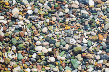 Closeup top view horizontal flatlay photography of many colorful vivid smooth stones at sea beach. Abstract organic background.