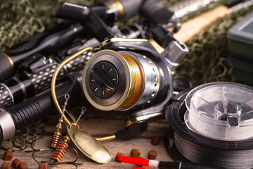 Fishing rods and spinnings in the composition with accessories for fishing on the old background on...
