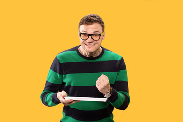 A man holds a keyboard in his hand and is very happy about his victory. Handsome smiles hard and clenched his hand into a fist. Studio photo.