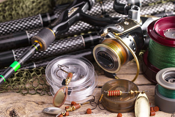 Fishing rods and spinnings in the composition with accessories for fishing on the old background on the table