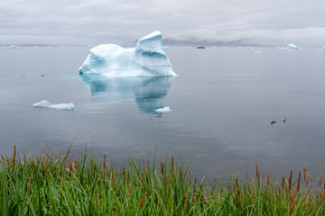 An iceberg floats in the harbor of a small Inuit village in Greenland