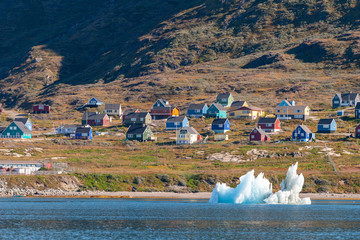 View of a small Inuit village from the sea with floating icebergs.