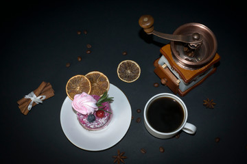 Fruit cake and a cup of coffee on a black table.