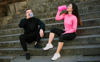 Modern fitness couple making break in a park during workout