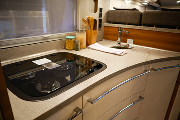Fototapeta na wymiar Interior of luxury caravan. Detail photo of coach with equipment.Kitchen