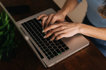 Close-up of women's hands are typing on the laptop keyboard, an enters password. Unrecognizable woman is writing email on laptop at the office or home, closeup. Concept of office life, top view.