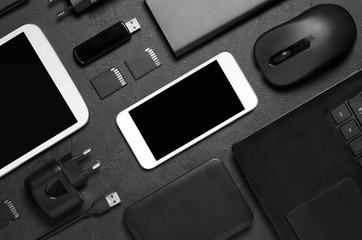 Electronic gadgets on a black concrete background. Concept of accessories for successful business. Flat lay.
