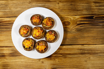 Baked mushrooms stuffed with minced meat, mushroom, paprika, onion and cheese on wooden table. Top view