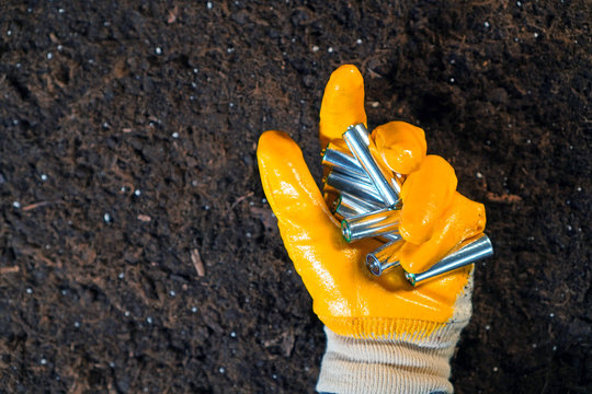 Used Batteries In A Hand On Earth Background. Proper Battery Disposal Concept.