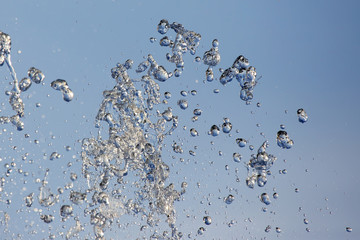 Splashes of flying water from the fountain against the blue sky
