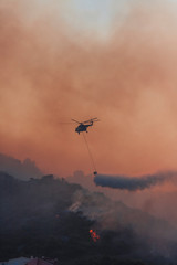 Fototapeta na wymiar Fire fighting helicopter with waterbag on his way to combat the forest fire