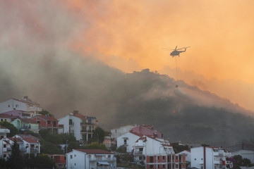 Fire fighting helicopter with waterbag on his way to combat the forest fire