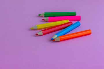 Colored pencils for drawing on a pink background. Copy space. Back to school backdrop. Kid's stationery. School supplies.