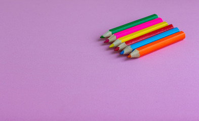 Colored pencils for drawing on a pink background. Copy space. Back to school backdrop. Kid's stationery. School supplies.