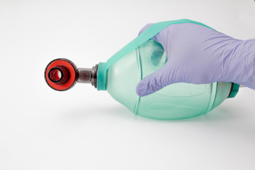 An AMBU bag pressed by a doctor with blue glows isolated