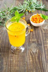 Hot vitamin tea with sea buckthorn and mint leaves on a dark wooden background. Organic drink