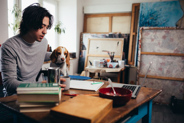 self employed young man with his dog in his home work place