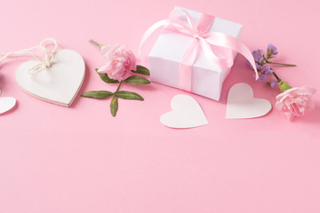 Fototapeta na wymiar Gift, wooden white heart and flowers on pink background