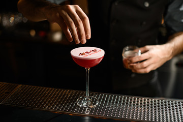 Close-up of bartender decorating alcohol cocktail on bar counter