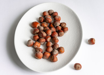 hazelnuts, hazelnuts on a white plate, skattered hazelnuts on a plate, nuts, white plate, nuts on a white backdrop