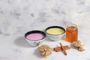 Turmeric latte and pink golden milk for a better sleep, ginger and cinnamon on a gray table, a fashionable relaxing drink, has antioxidant properties, helps detoxify the body, a place for text