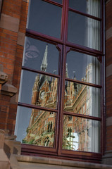 Neo-gothic architectural style building reflected in a window during a sunny and bright morning