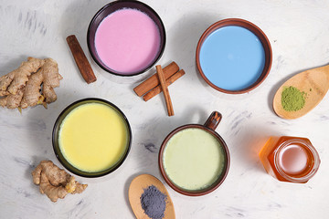 An assortment of colorful latte Japanese tea, matcha green, blue, pink moon milk, golden milk, ginger and cinnamon, top view. A fashionable healthy drink has anti-inflammatory properties.