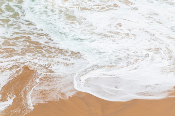 Ocean coast, moviment white foam on sand.