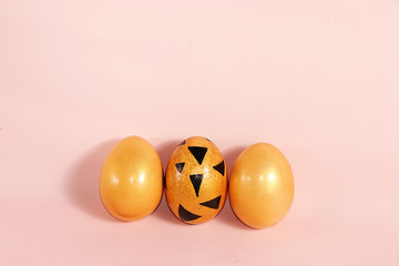 Decorated golden easter eggs on a pink background. Minimal holiday concept. Happy easter background. Creative painting of eggs at home, the idea of simple drawings for coloring